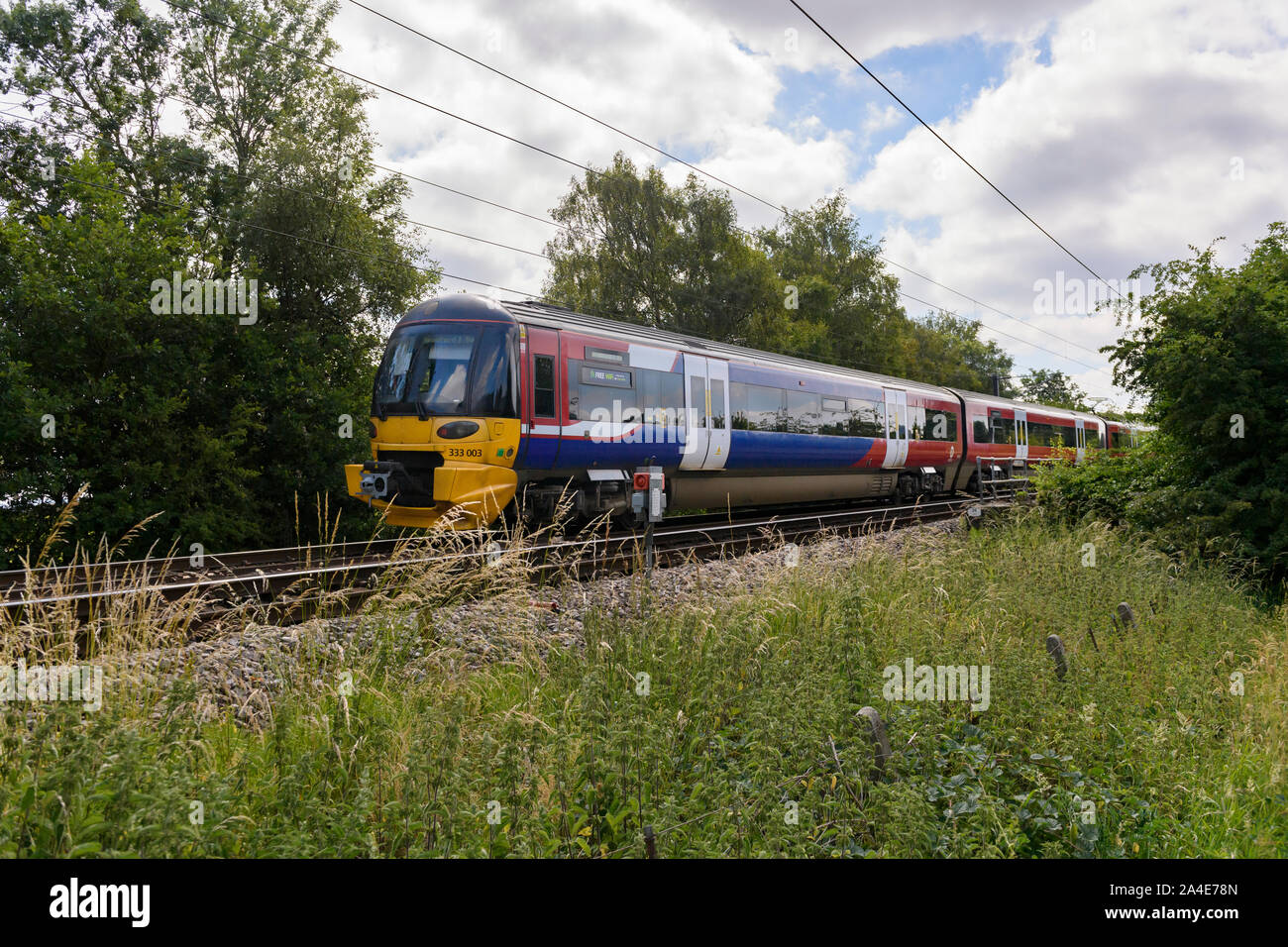 Nord del servizio ferroviario passeggeri che viaggiano in treno, cabina, binari ferroviari & cavi sovrastanti - Wharfedale linea nel West Yorkshire area metropolitana, Inghilterra, Regno Unito. Foto Stock
