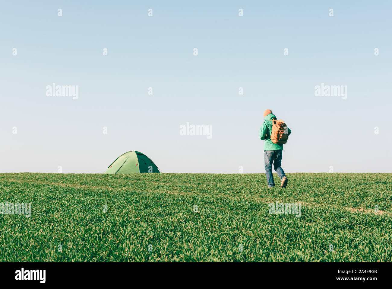Turistico con zaino andando a la sua tenda sul campo estivo. Concetto di viaggio Foto Stock