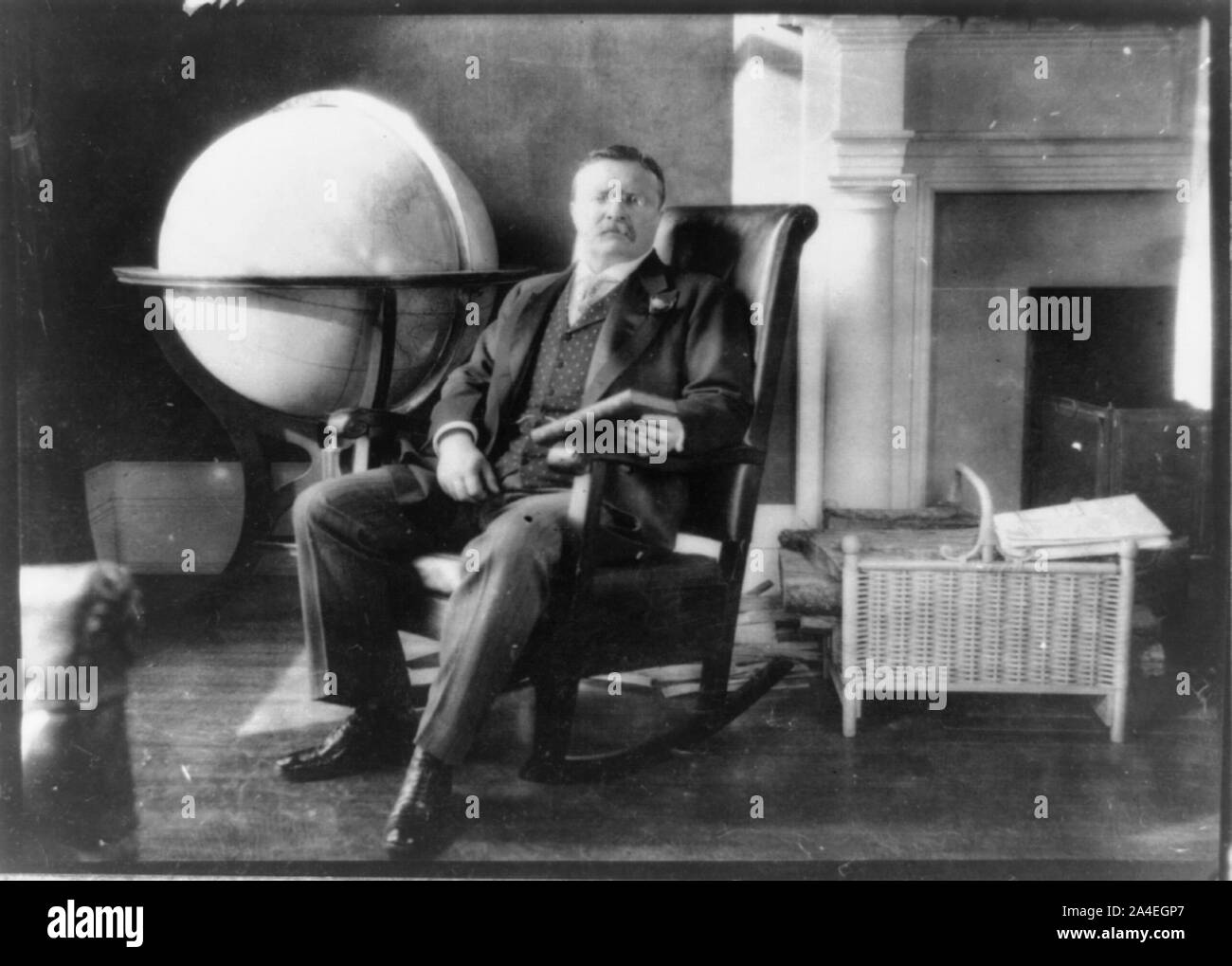 Theodore Roosevelt, ritratto a figura intera, seduto da globe e mantello, rivolta leggermente a destra, azienda prenota Foto Stock