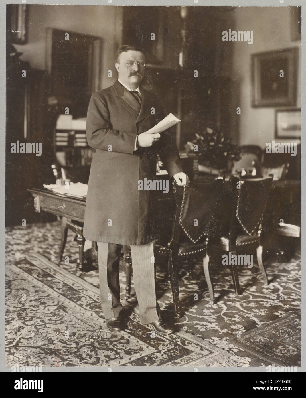 Theodore Roosevelt, ritratto a figura intera, in piedi da tavolo, rivolto verso destra Foto Stock