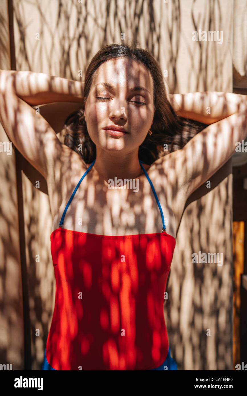 Giovane donna, a prendere il sole sotto l'ombra di una palma. Foto Stock