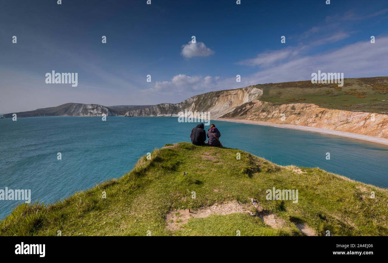 Due persone sedute sul ciglio della scogliera Worborrow Tout che guarda alla Baia di Worborrow vicino Tyneham, Dorset, Regno Unito Foto Stock