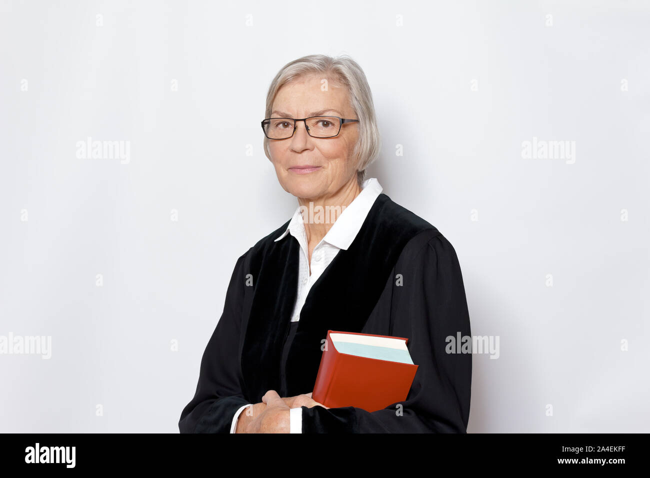 Competenza femminile concetto: Coppia donna tedesca in un giudice nero abito della holding di un testo legislativo libro. Foto Stock