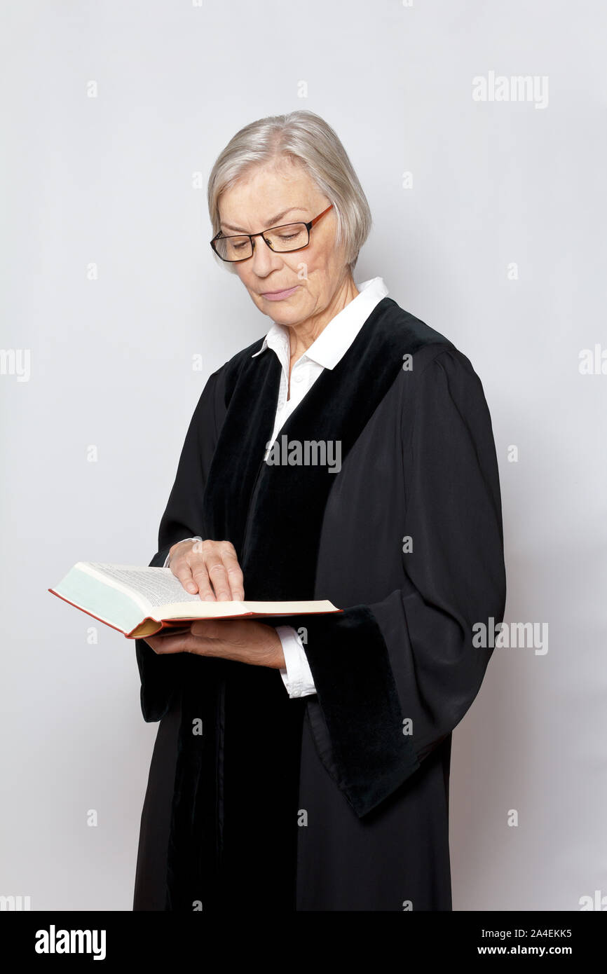 Giurisdizione tedesca concetto: anziani giudice in veste nera la lettura di un libro con il testo della costituzione tedesca. Foto Stock
