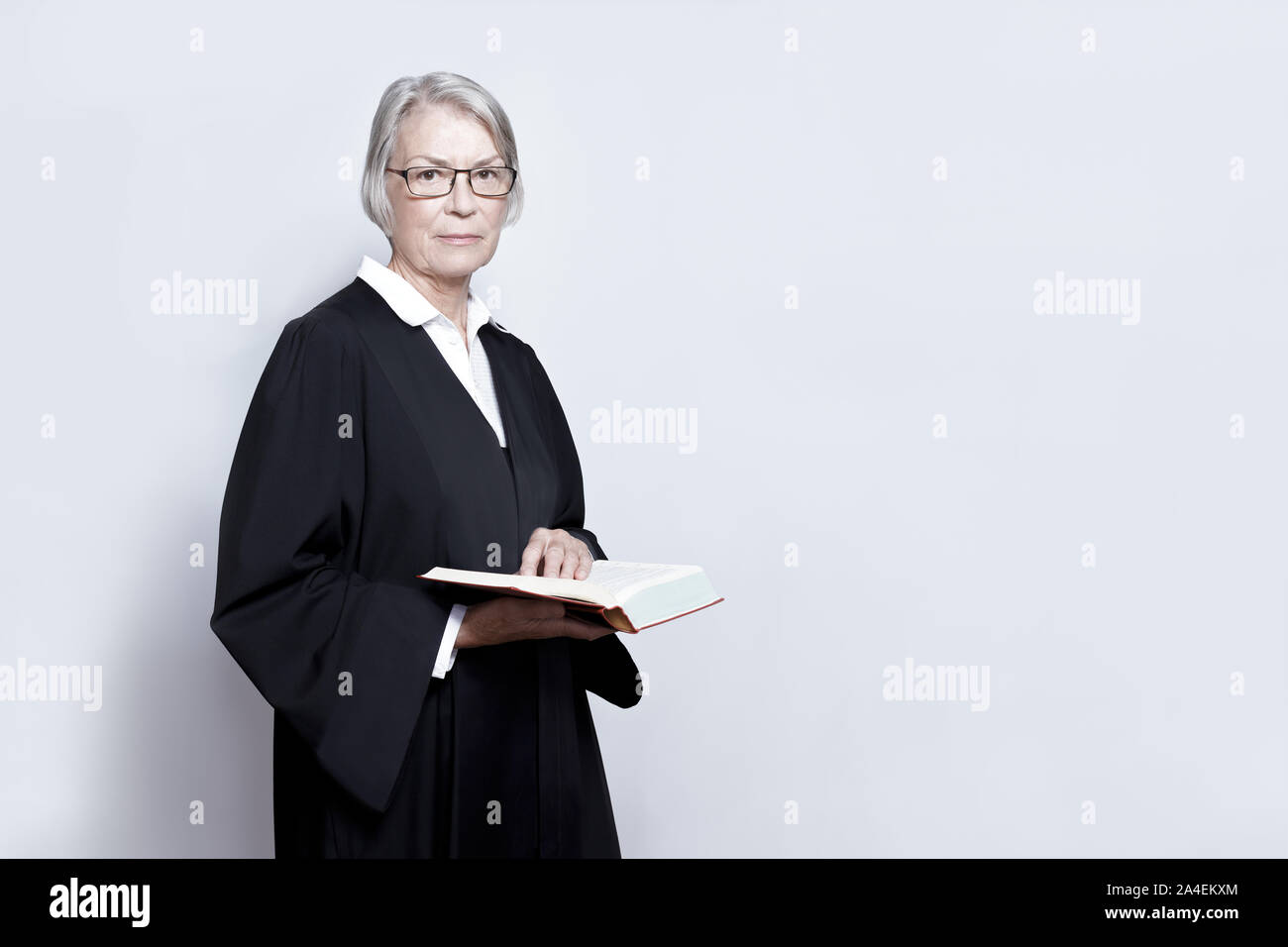Avvocato femmina concetto: donna matura in un abito nero tenendo un testo legislativo prenota, copia dello spazio. Foto Stock