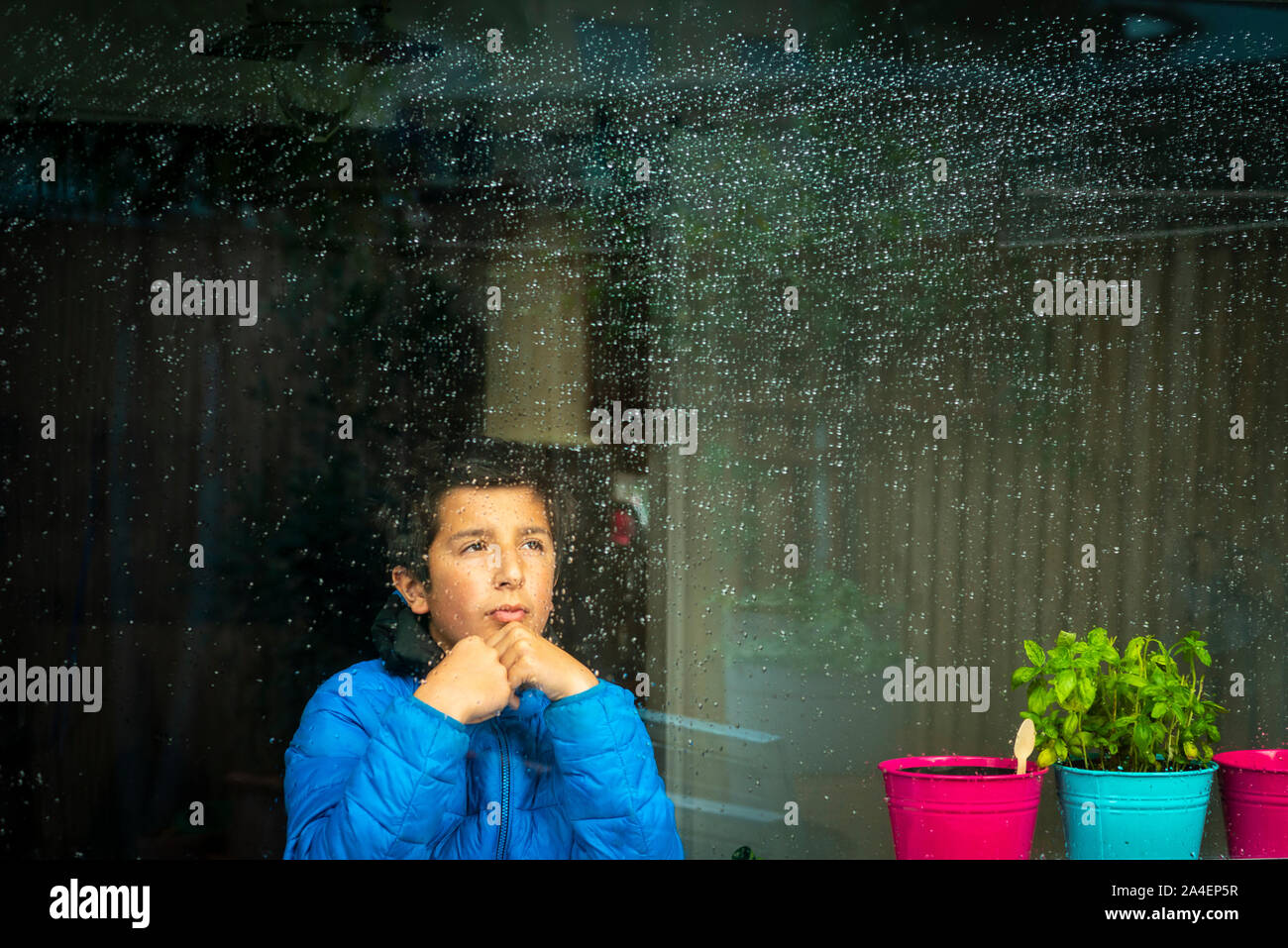 Ragazzo che guarda a pioggia al di fuori Foto Stock