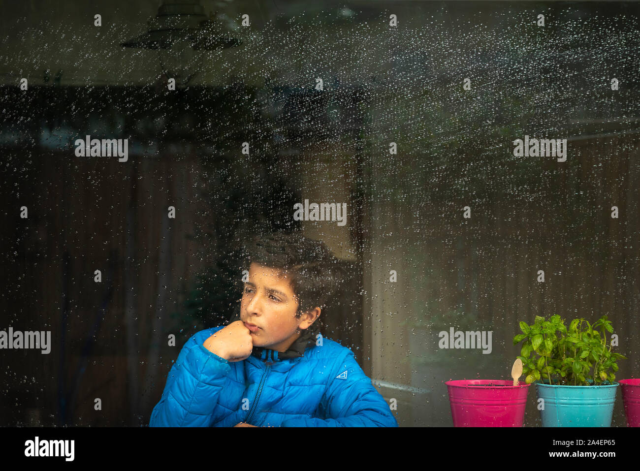 Ragazzo che guarda fuori dalla finestra in una piovosa giornata inverni, Surrey, Regno Unito Foto Stock