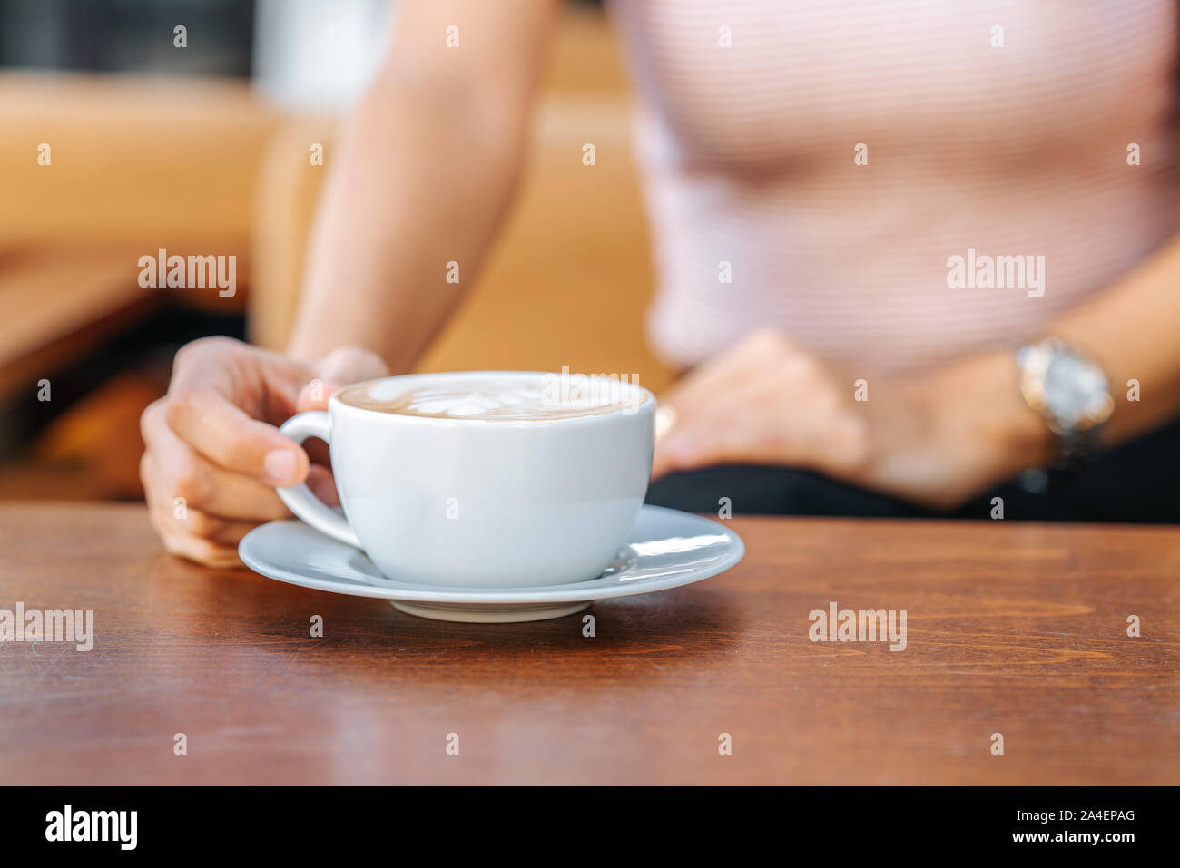 Giovane donna seduta e la coppa di ritegno di caffè in un bar. Foto Stock
