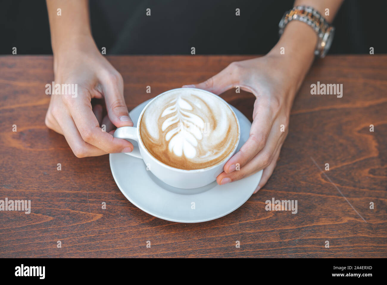 Giovane donna seduta e bicchiere di contenimento conformata con un caffè in una caffetteria. Foto Stock