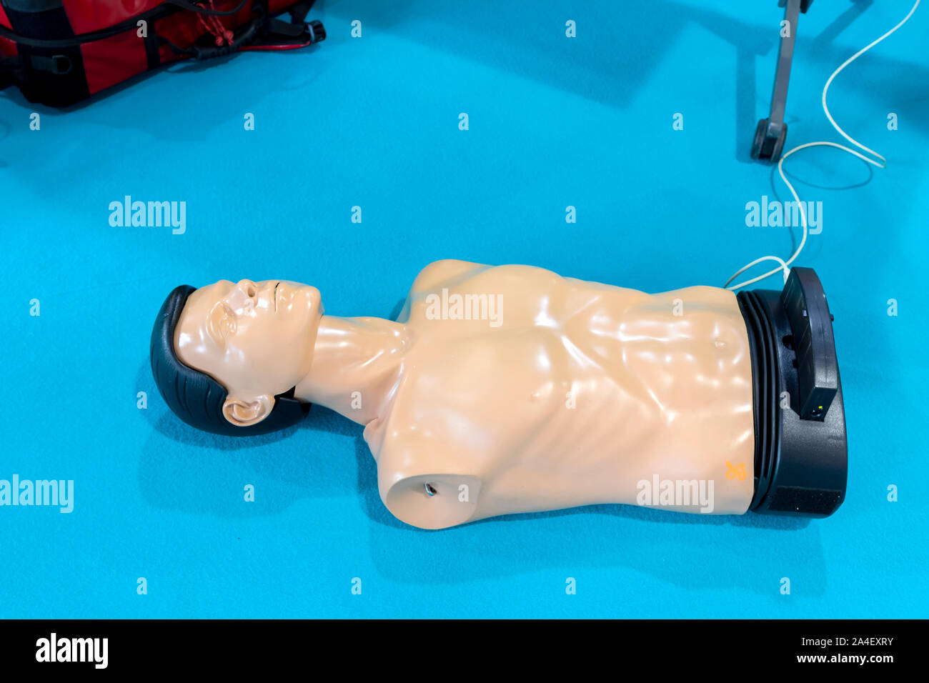 CPR manichino formazione giace a terra sulla moquette blu, cavo ad esso collegato. Foto Stock