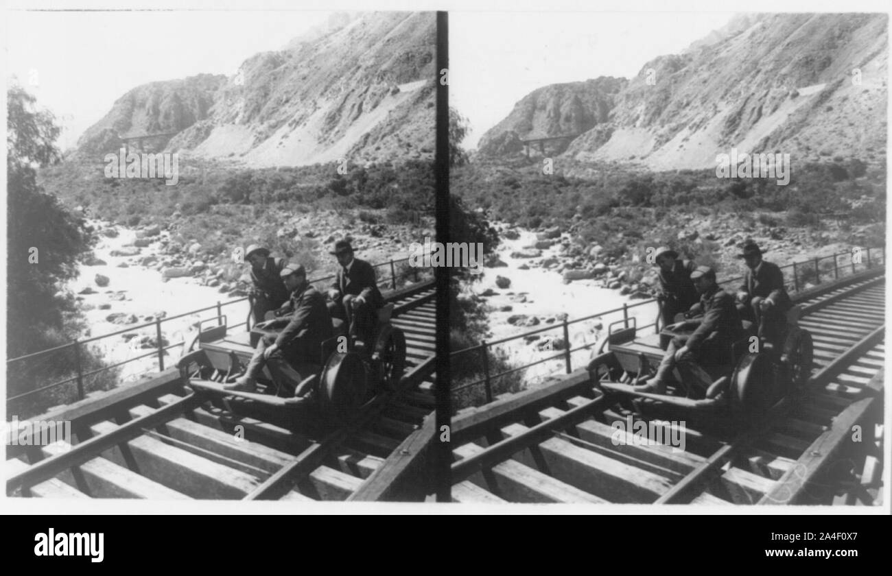 Tre uomini in un handcar andando oltre il ponte Foto Stock