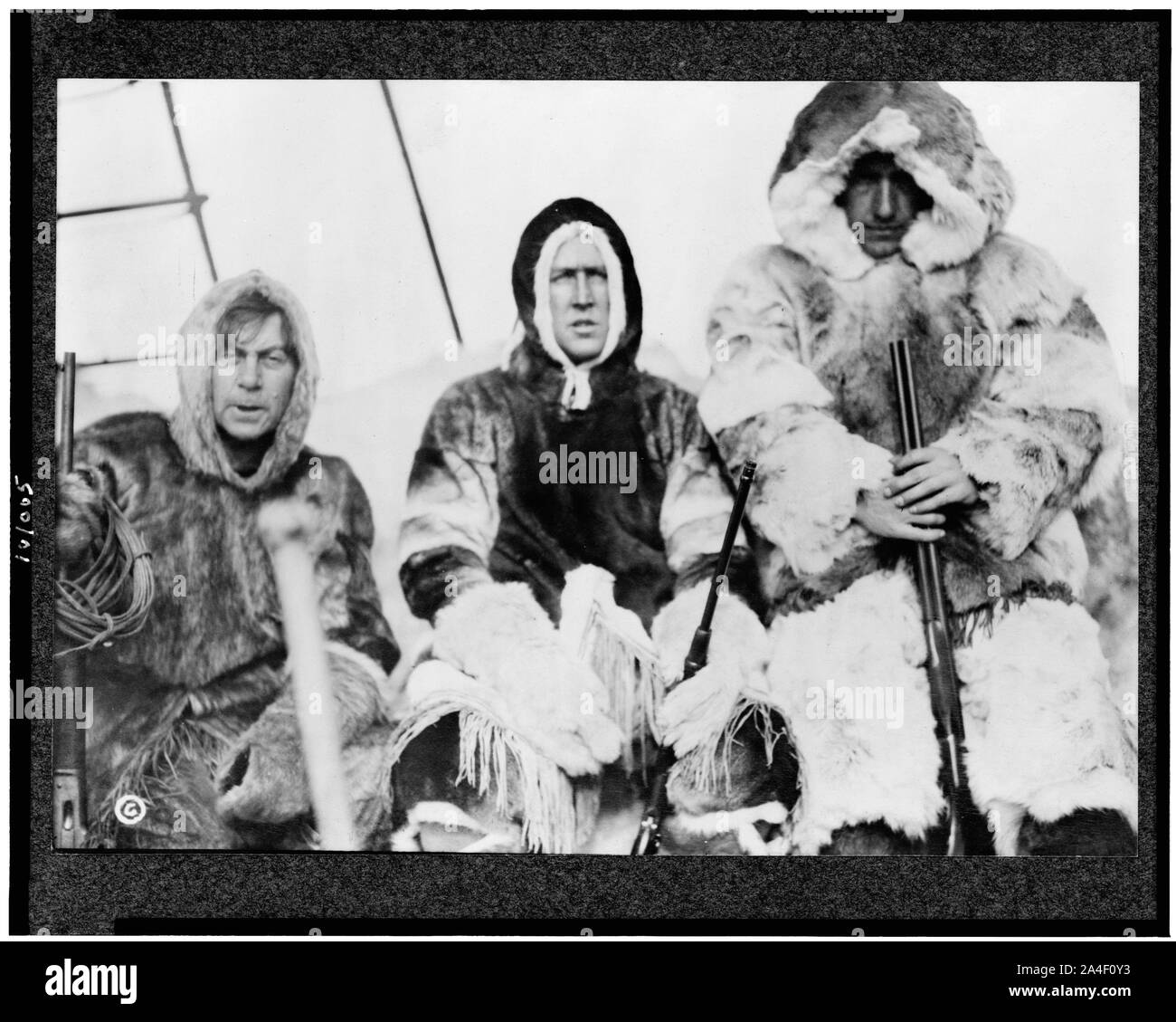 Tre uomini in pelliccia eskimo holding cannoni sulla nave durante la spedizione artica Foto Stock