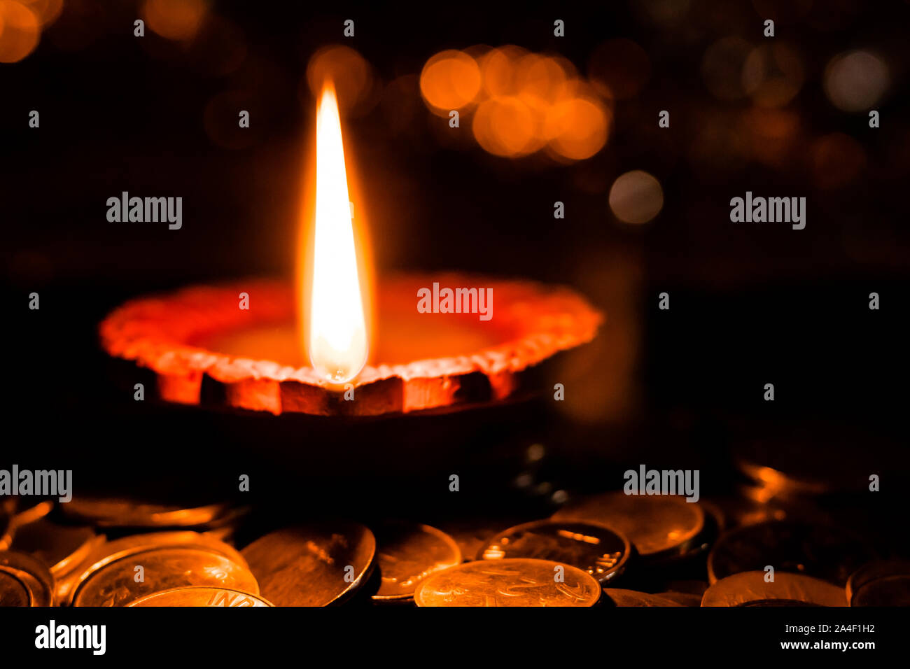 Prospettiva unica di una lampada di argilla usata per decorare le case di Diwali, posto su una pila di monete per la prosperità concept Foto Stock