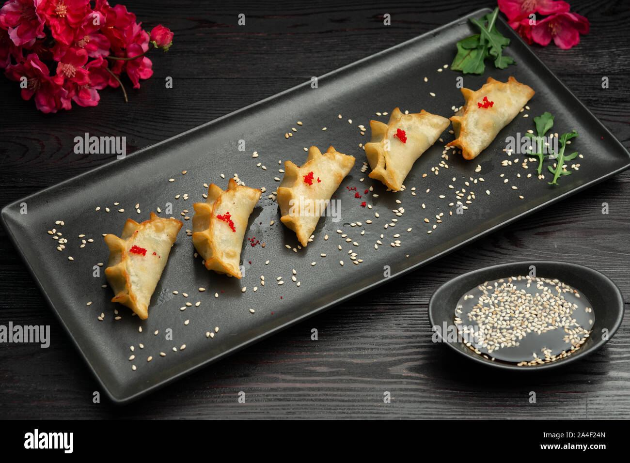 Ebi gedza cinese gnocco fritto con gamberi e verdure in una piastra nera su sfondo scuro, serviti con salsa Foto Stock