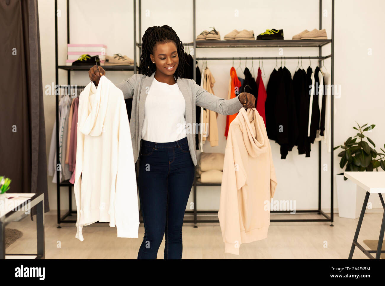 African American donna scegliendo Aggiornamenti stagionali in negozio di abbigliamento Foto Stock