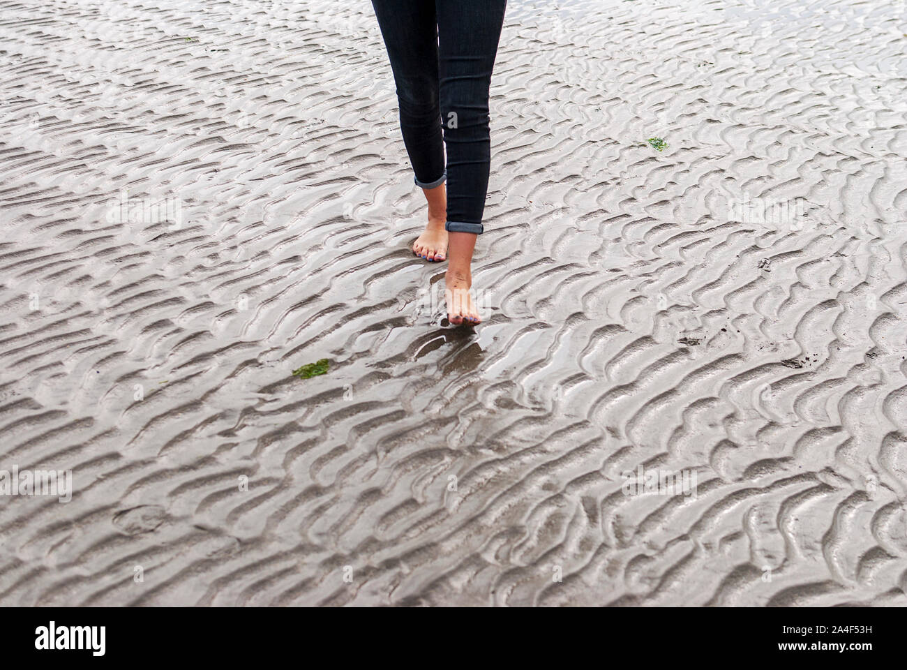 Giovane donna camminare e giocando sulla spiaggia sabbiosa e lasciando tracce in spiaggia. Killbrittain, Kilbrittain beach, Irlanda. Foto Stock