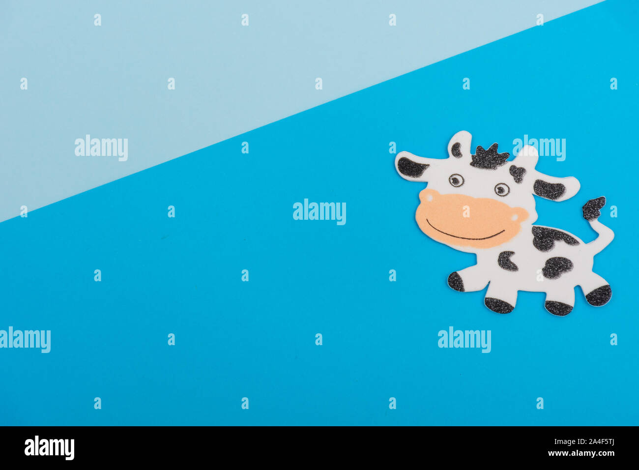 Cartoon in bianco e nero il latte di vacca sorridente su un luminoso blu e azzurro piatto sfondo laici con copia spazio disponibile. Concetto. Foto Stock