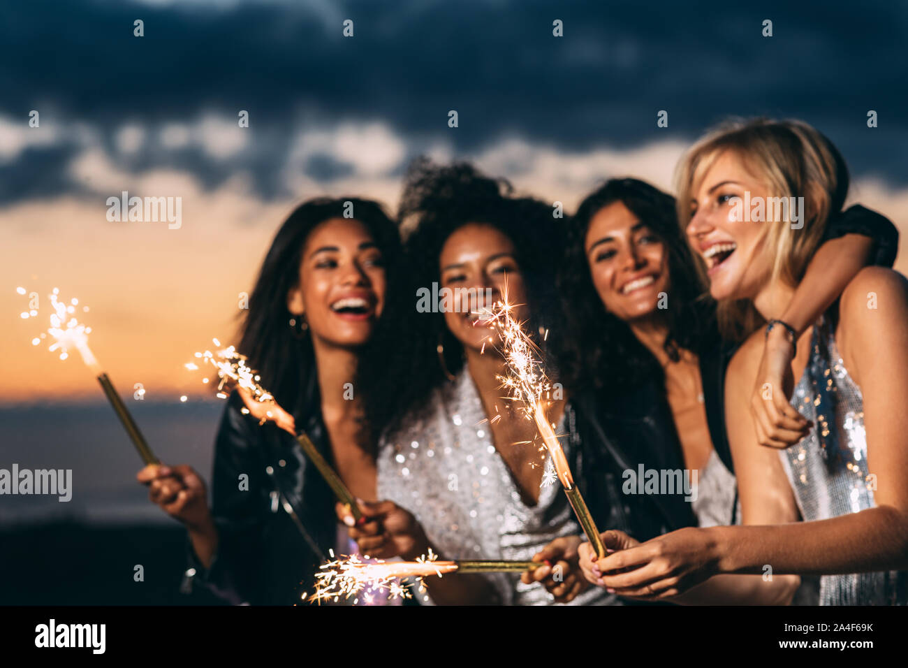 Close up felici donne azienda botti al tramonto Foto Stock