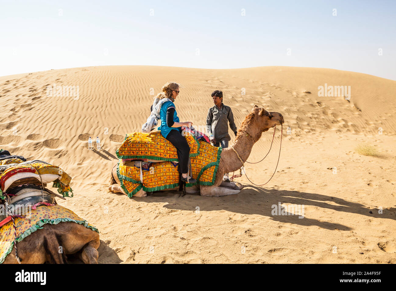 Un cammello conducente istruire un turista su come cavalcare un cammello, il Deserto di Thar, Rajasthan, India. Foto Stock