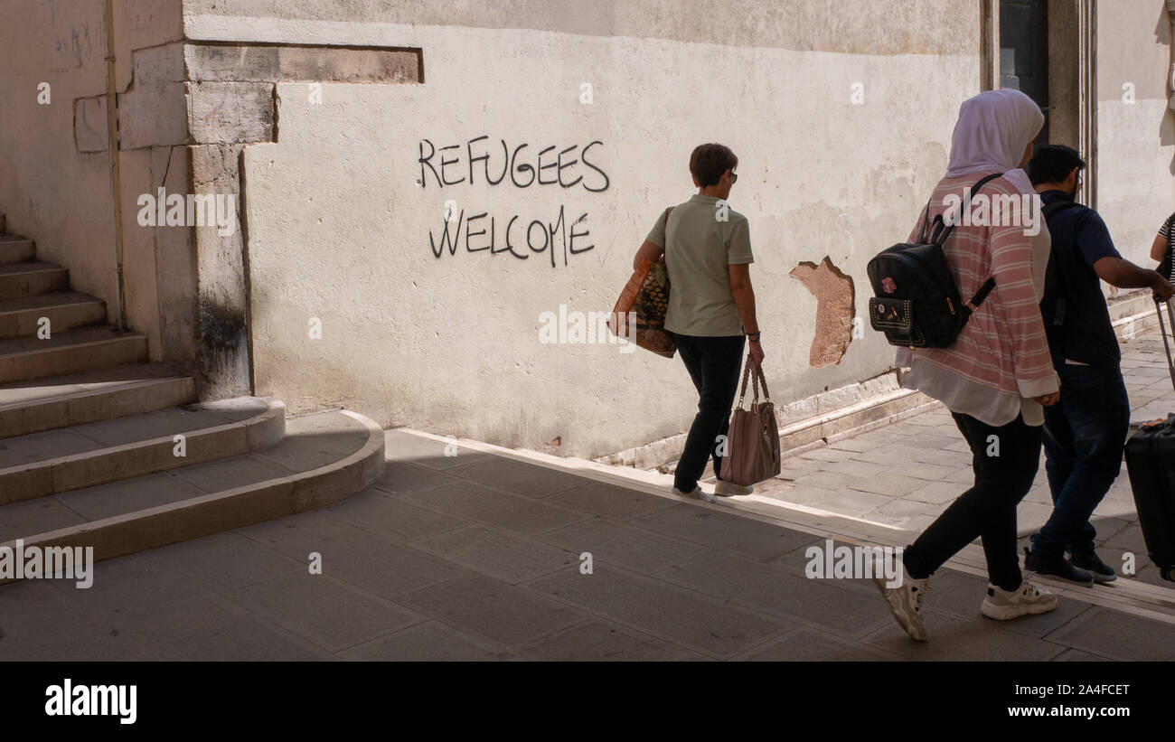 Graffiti con lo slogan politici "profughi" Benvenuto su una parete a Venezia Foto Stock