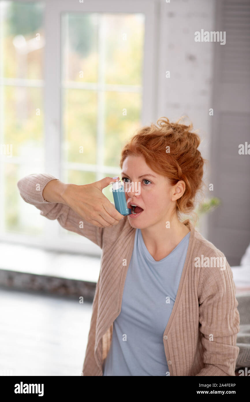 Donna con asma mediante inalatore mentre sensazione di cattivo Foto Stock