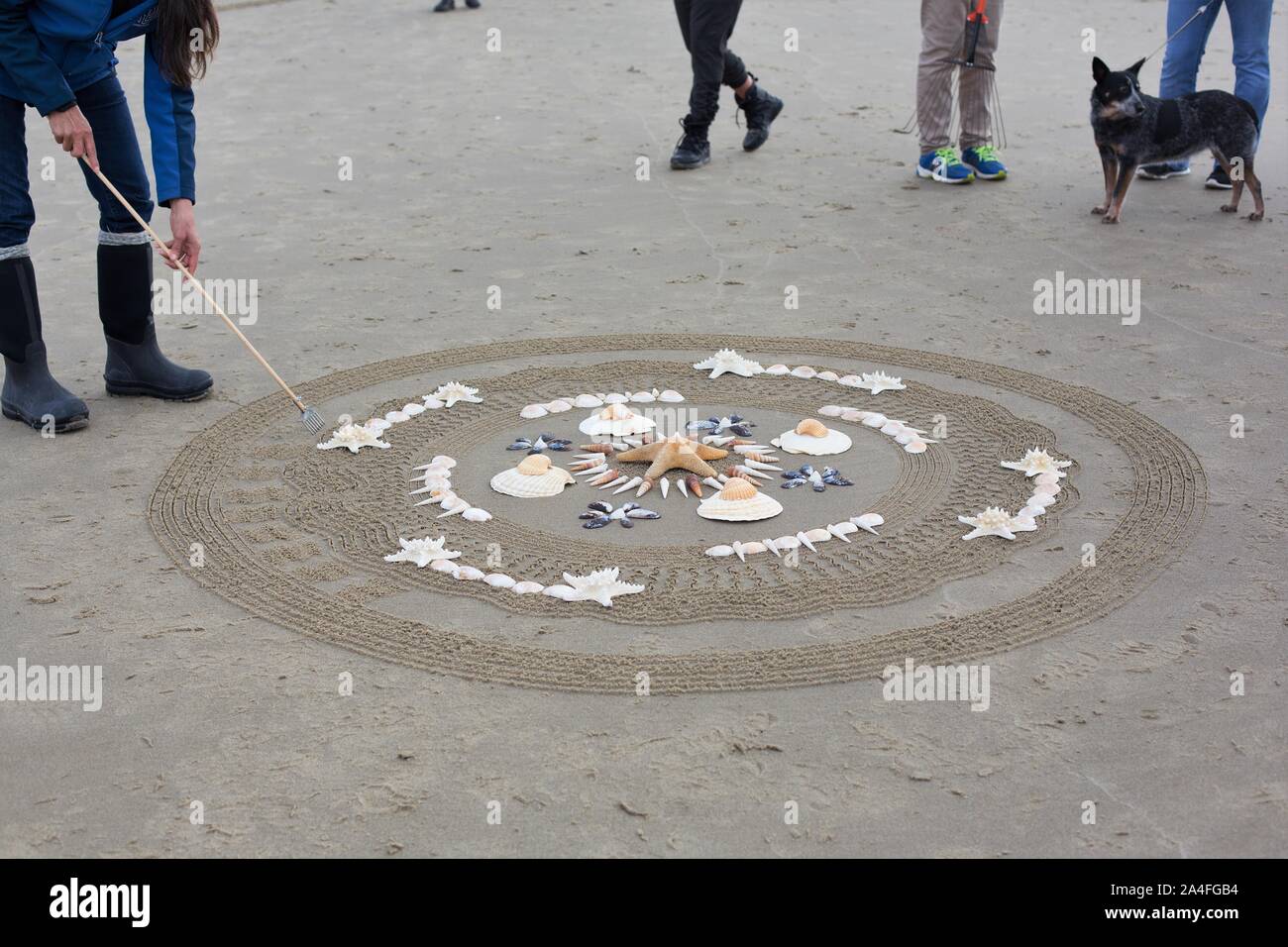 Un artista creando un mandala nella sabbia a cerchi nel labirinto di sabbia evento alla spiaggia Heceta a Firenze, Oregon, Stati Uniti d'America. Foto Stock