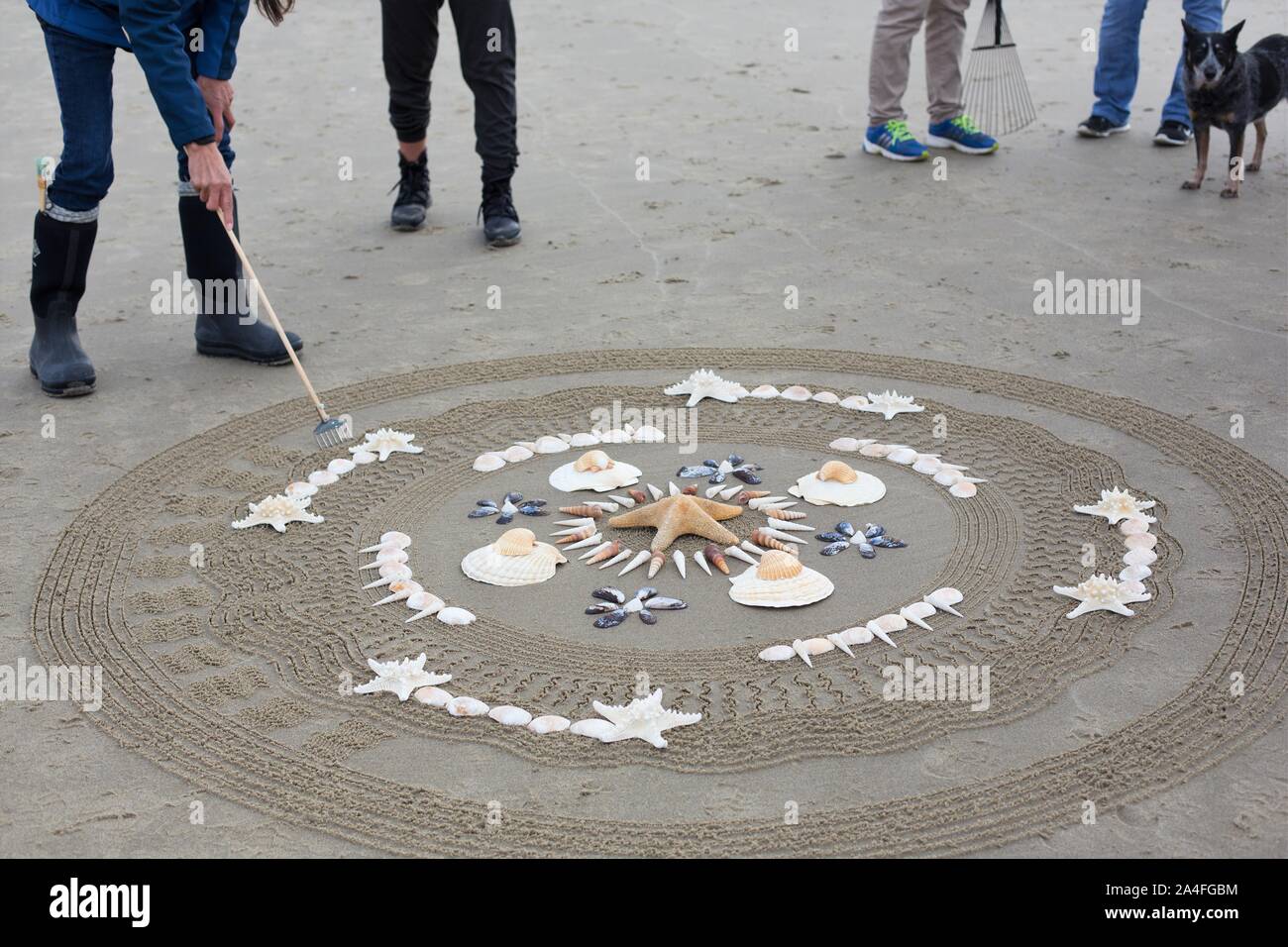Un artista creando un mandala nella sabbia a cerchi nel labirinto di sabbia evento alla spiaggia Heceta a Firenze, Oregon, Stati Uniti d'America. Foto Stock