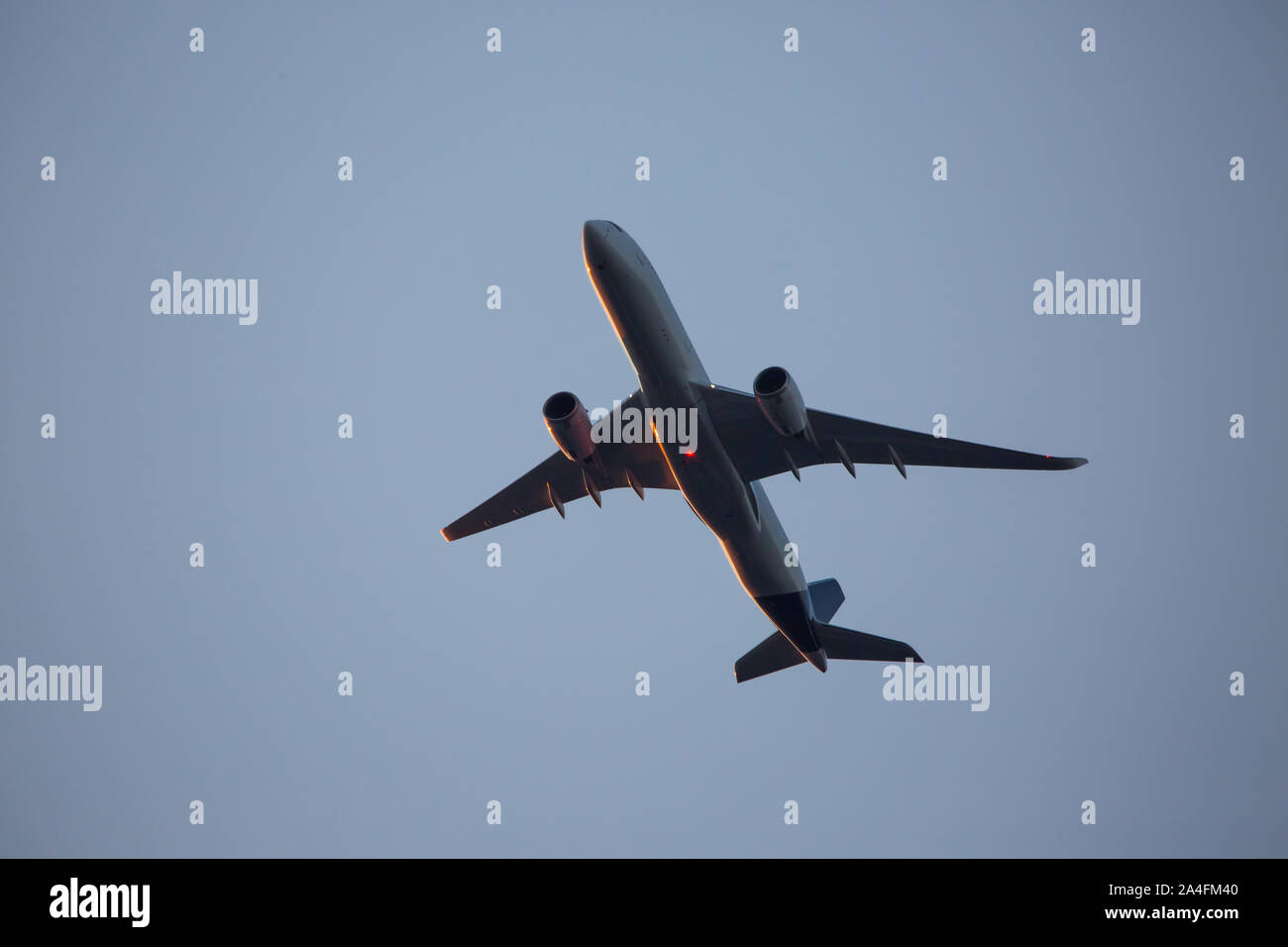 Un aereo commerciale a bassa altitudine al tramonto, il profilarsi di un pallido cielo blu. Foto Stock