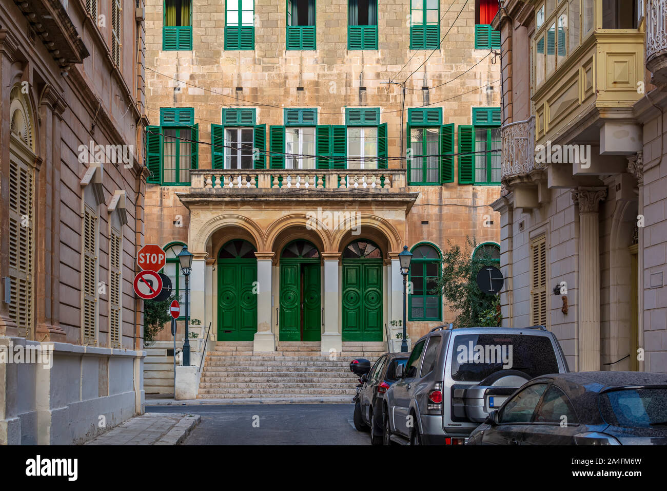 Edificio con facciata tradizionale maltese finestra verde persiane in Sliema Malta, colorate di arancione con la luce del sole serale. Autentica urbano maltese sce Foto Stock