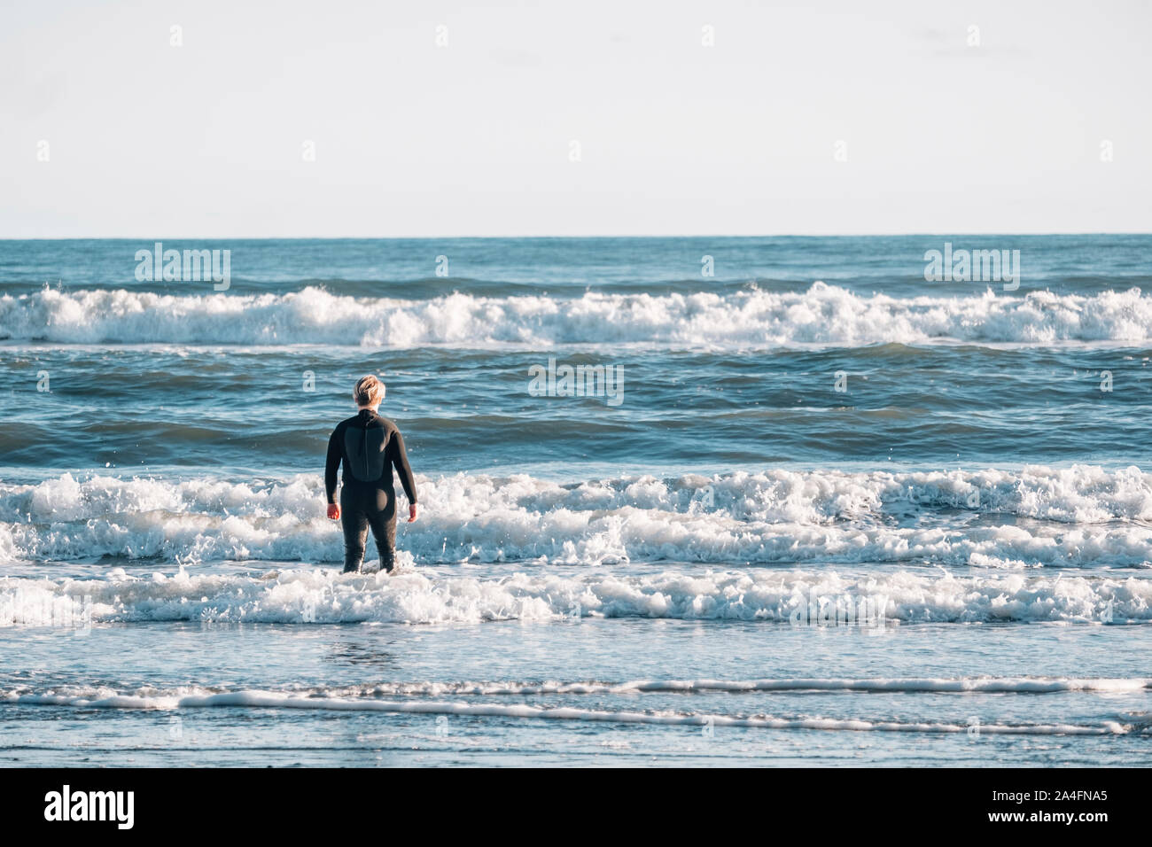 Tween ragazzo indossa una muta in piedi il surf in spiaggia Foto Stock