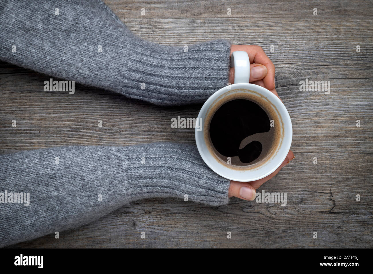 Mani tenendo una tazza di caffè nero Foto Stock