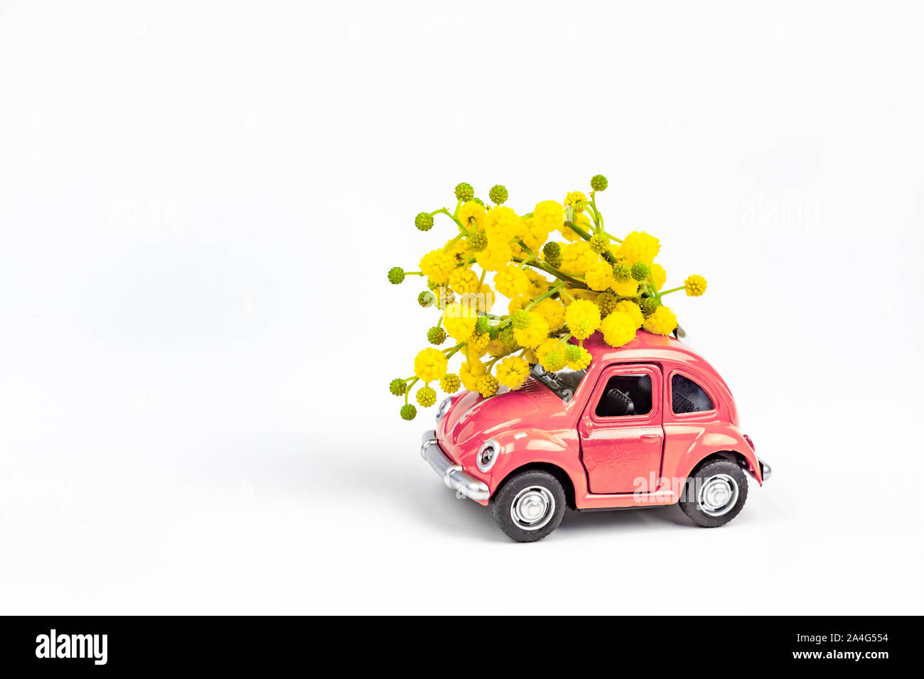 Mosca, Russia - 23 Febbraio 2019: 8 Marzo Giornata Internazionale della Donna con scheda Modello giocattolo auto retrò consegna bouquet di fiori di mimosa sul retro bianco Foto Stock