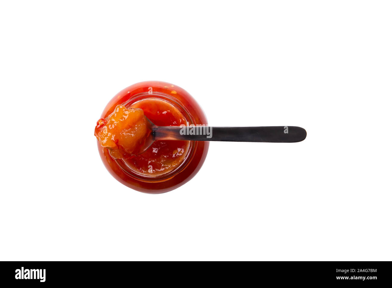 Isolato su sfondo bianco un vasetto di marmellata o confettura di pomodoro fragola apple frutta di arancia ciliegia con un cucchiaio fotografato dall'alto verso il basso su di un bianco puro Foto Stock