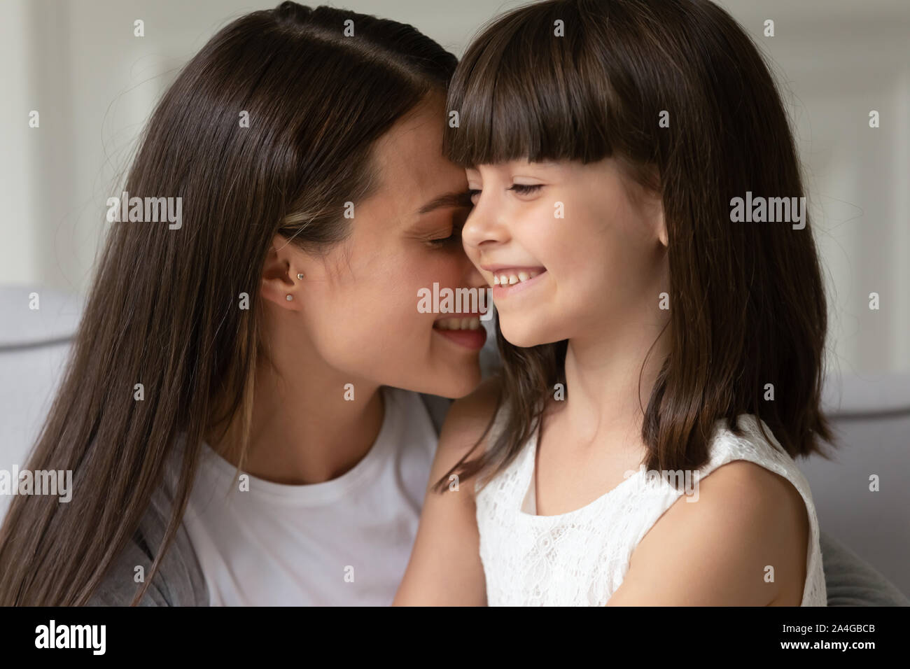Colpo alla testa close up felice giovane madre incollaggio piccola figlia. Foto Stock