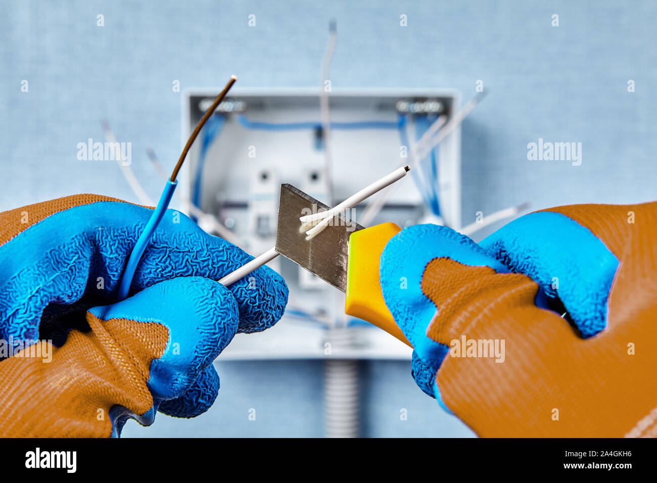 L'uso di un coltello di costruzione durante il montaggio di un quadro elettrico in un edificio residenziale, rimozione di isolamento dall'estremità di un filo di rame. Home eleggere Foto Stock