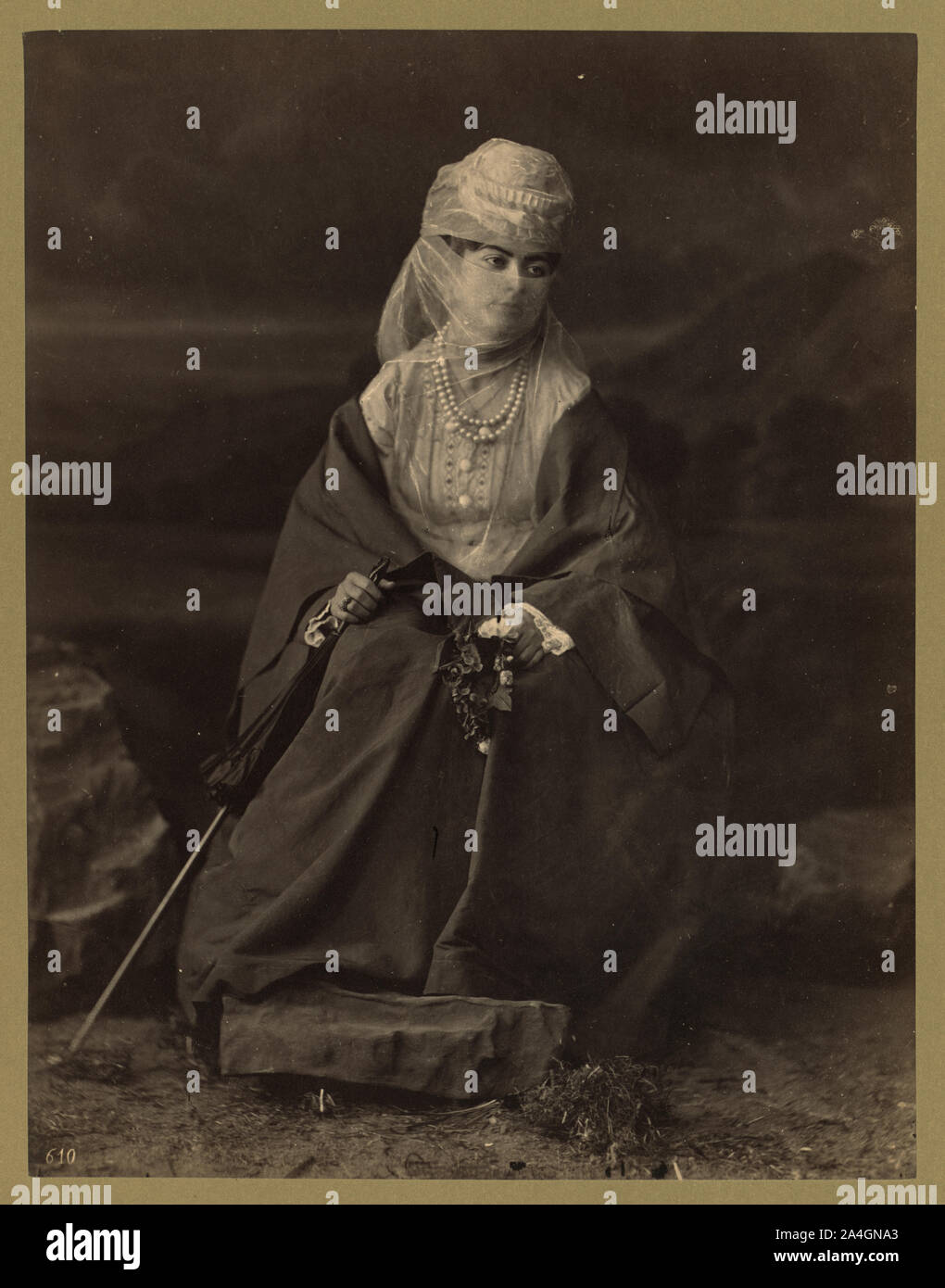 Donna turca, ritratto a figura intera, seduto, rivolto verso la parte anteriore, tenendo parasol e fiori Foto Stock