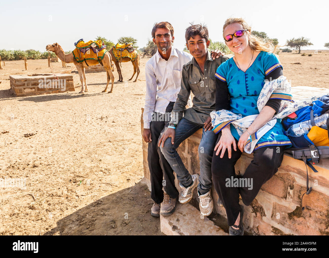 Un turista che posano per una foto con i suoi due piloti del cammello/guide su un cammello trek tour. Kanoi, Rajasthan, India. Foto Stock