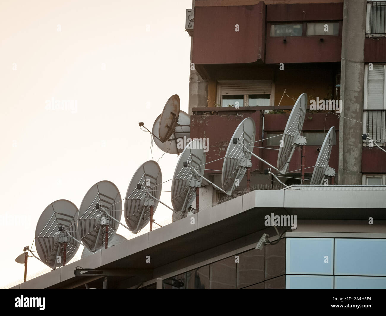 Parabole satellitari e antenne sul display nella parte superiore di un edificio aziendale al tramonto. Questi sono utilizzati per le comunicazioni e la trasmissione delle informazioni. Foto Stock