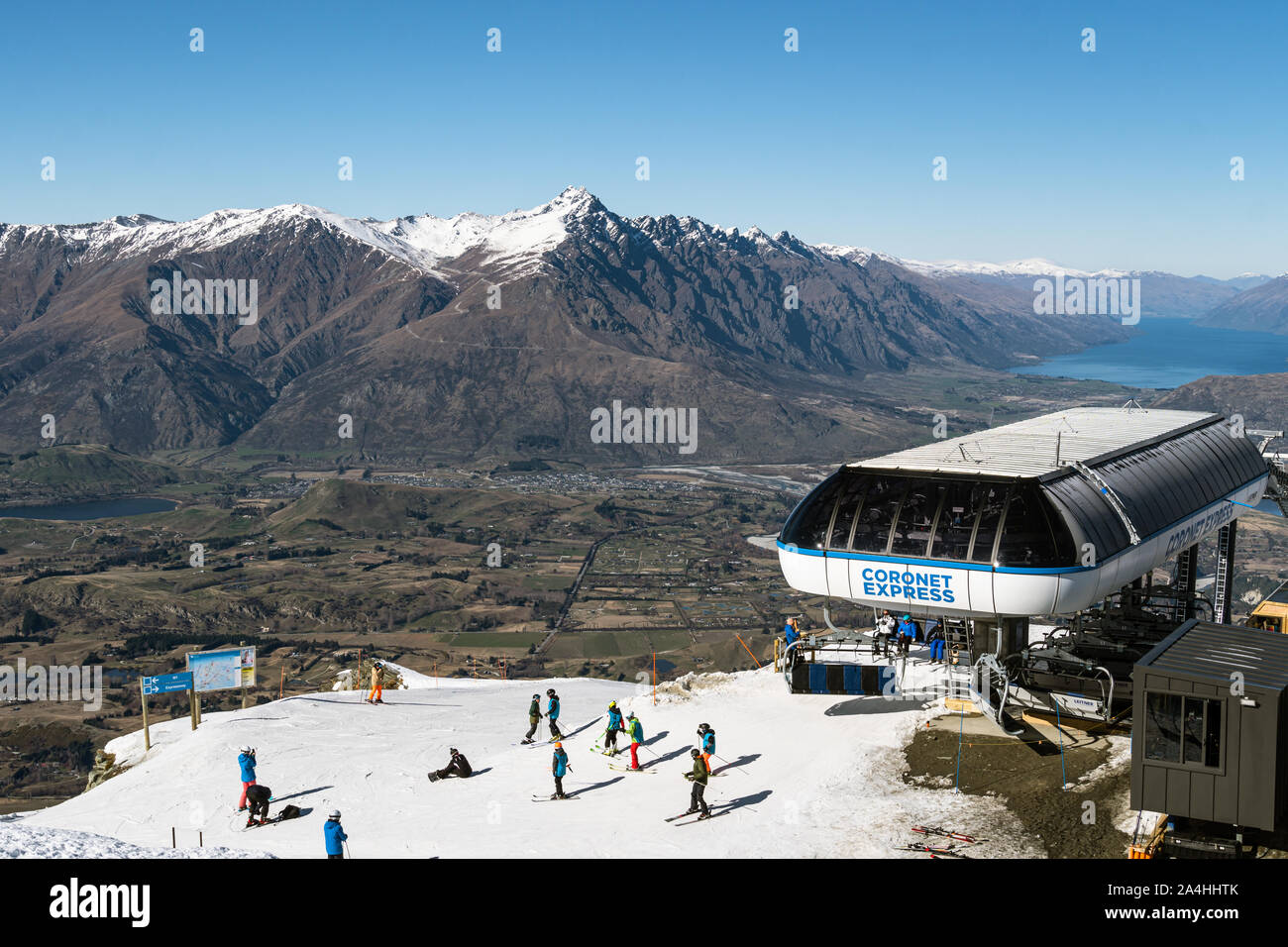 Queenstown, Nuova Zelanda - 7 Settembre 2019: sciatore e snowboarder ride una seggiovia in Coronet Peak ski resort in Nuova Zelanda in primavera con il lago di W Foto Stock