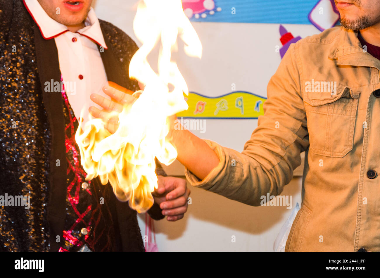 Un mago rende fire visualizzati dal partecipante la mano, atto di magia con il fuoco Foto Stock