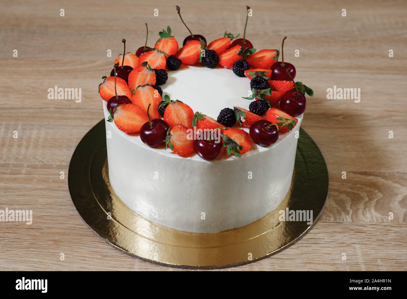 Bella torta con le fragole, ciliegia, blackberry e la crema su sfondo di legno. Foto Stock
