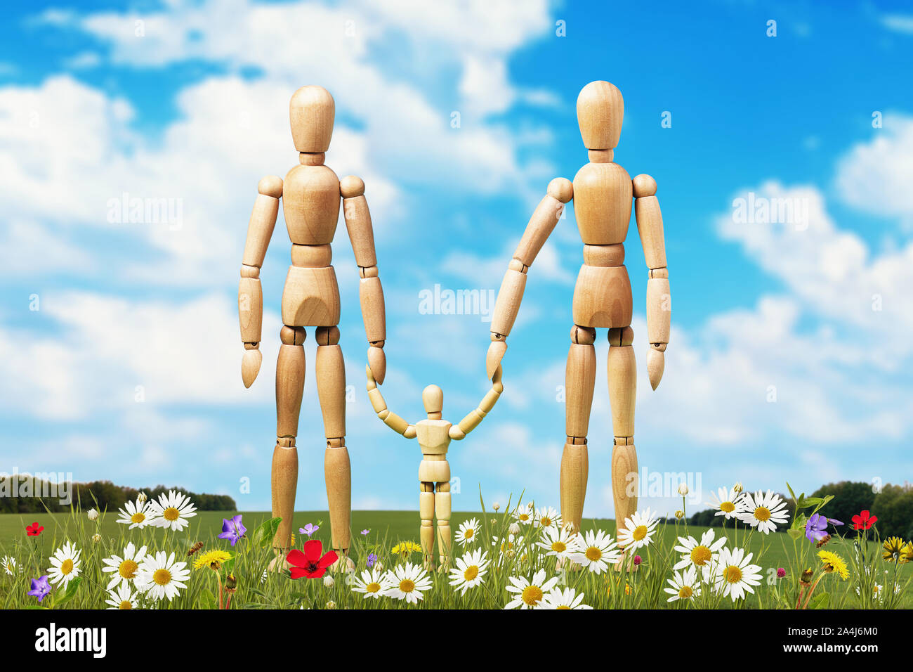 Una famiglia di manichini in legno su un prato circondato da fiori Foto Stock