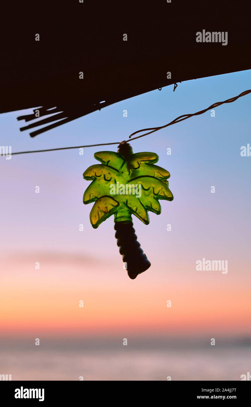Palm tree a forma di stringa di festa luce decorare un rustico bar sulla spiaggia cafe con un tramonto cielo e mare spiaggia sfondo - spiaggia tropicale simbolo di vacanza Foto Stock