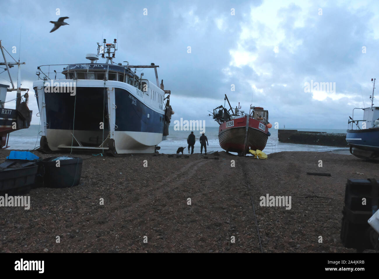 Hastings, East Sussex, Regno Unito. Il 15 ottobre 2019. I pescatori sulla Città Vecchia Stade all'alba, su un livello di grigio nuvoloso la mattina presto, ma con un bel giorno previsioni. Foto Stock