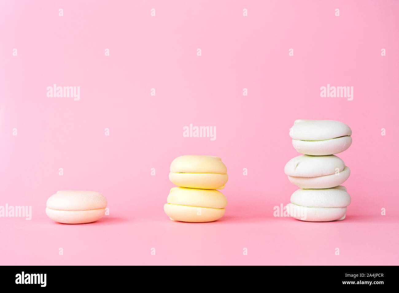 Pesca, giallo e il colore verde marshmallows su un pastello sfondo rosa Foto Stock