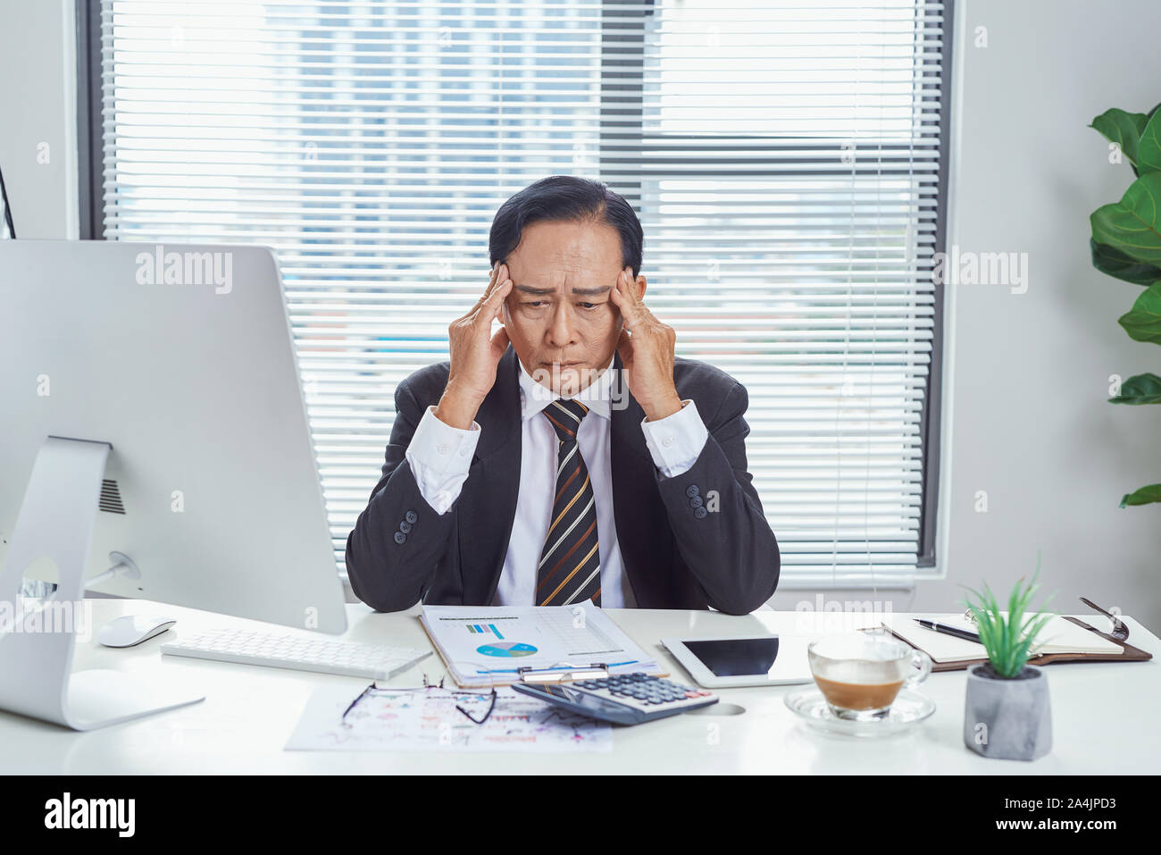 Di mezza età imprenditore asiatici sensazione stressato e frustrato mentre si lavora nella stazione di lavoro. Problema di business concept Foto Stock