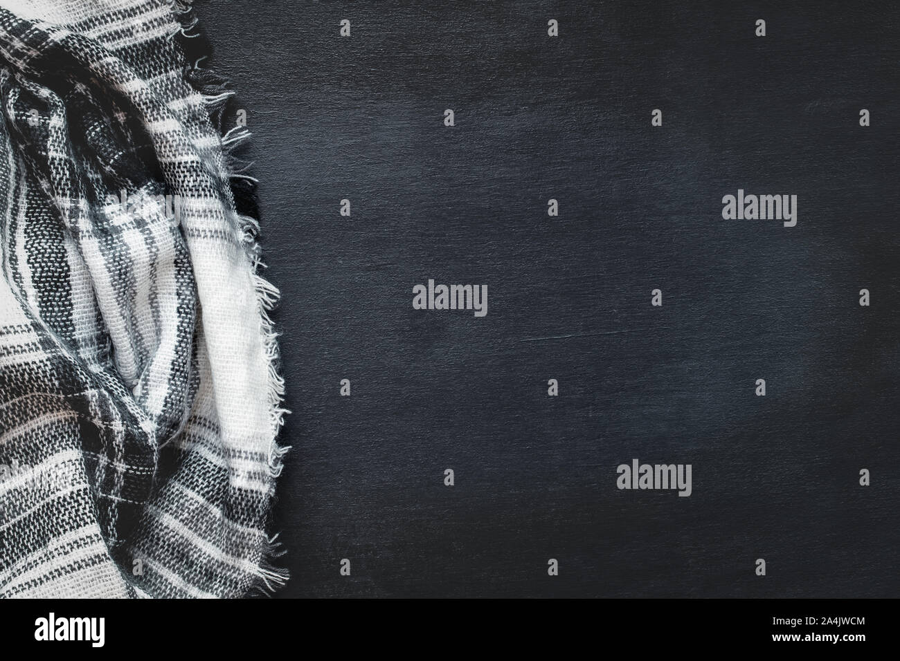 Riscaldare tessuto nero, bianco e grigio raggrinzato coperta su un nero lo sfondo di legno. Ripresa dall'alto vista superiore con spazio libero per il testo per lo sfondo. Foto Stock