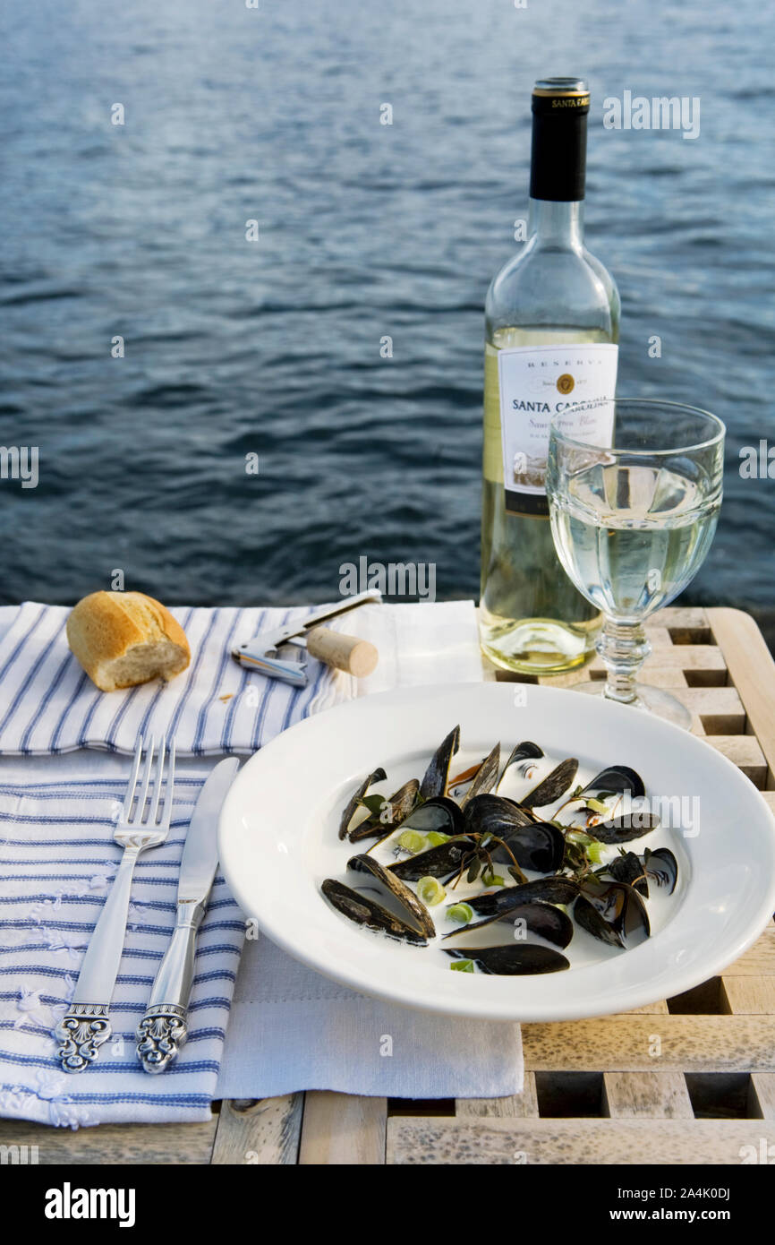 Cozze e vino bianco in riva al mare Foto Stock