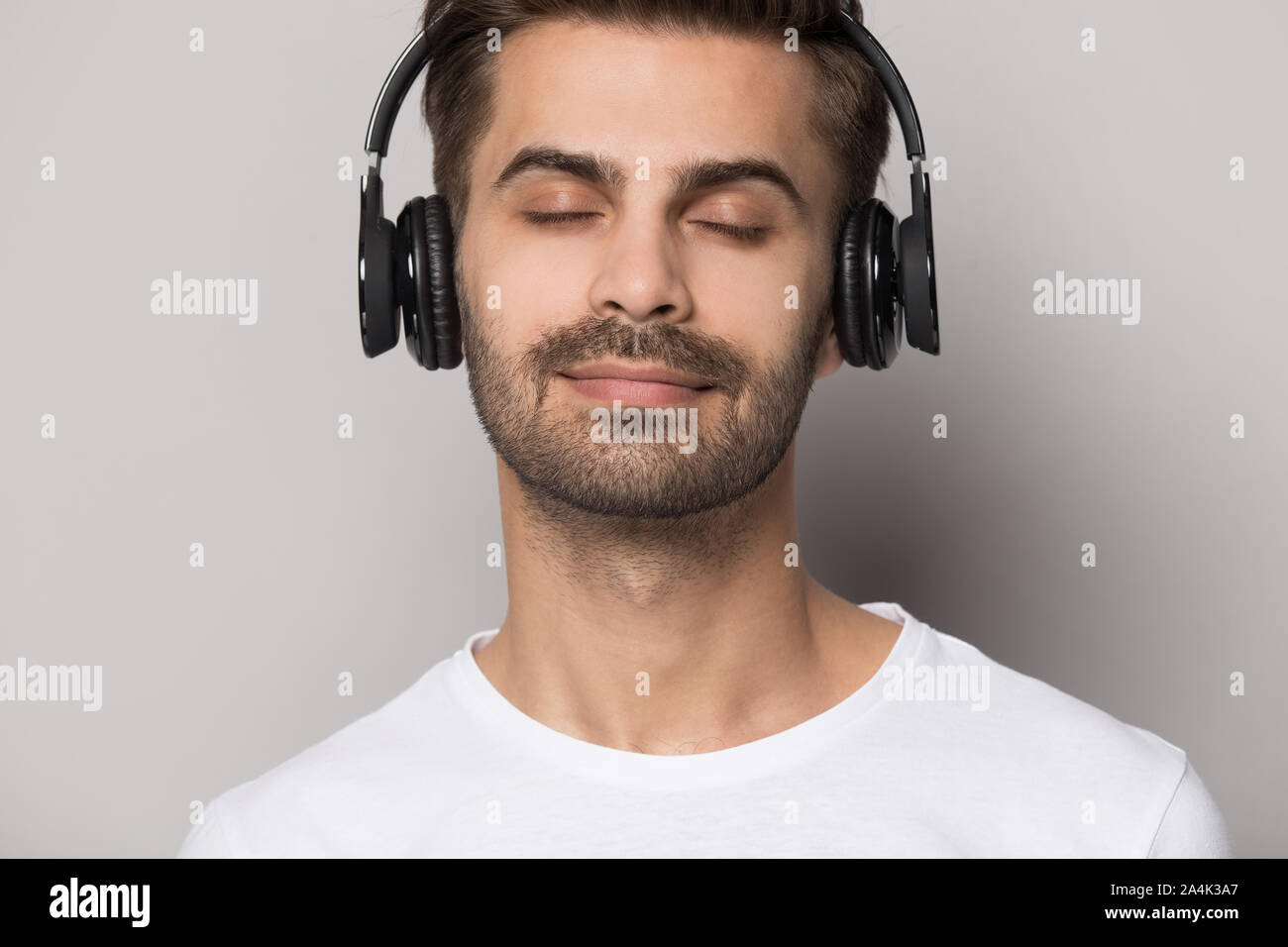 Close up uomo caucasico godetevi il suono in auricolari Bluetooth Foto Stock