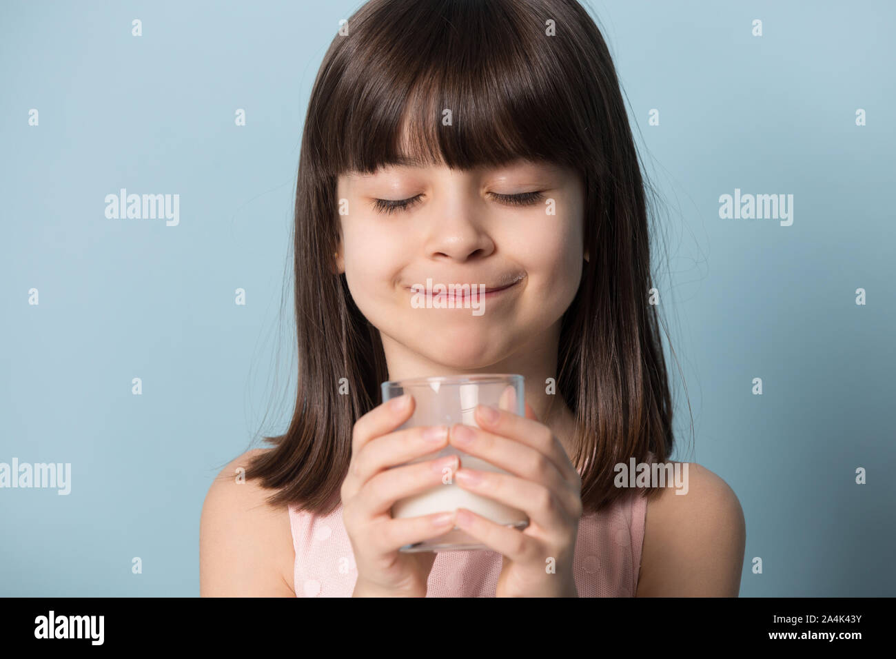 Felice bambina impianto di bere latte deliziosi dal vetro Foto Stock